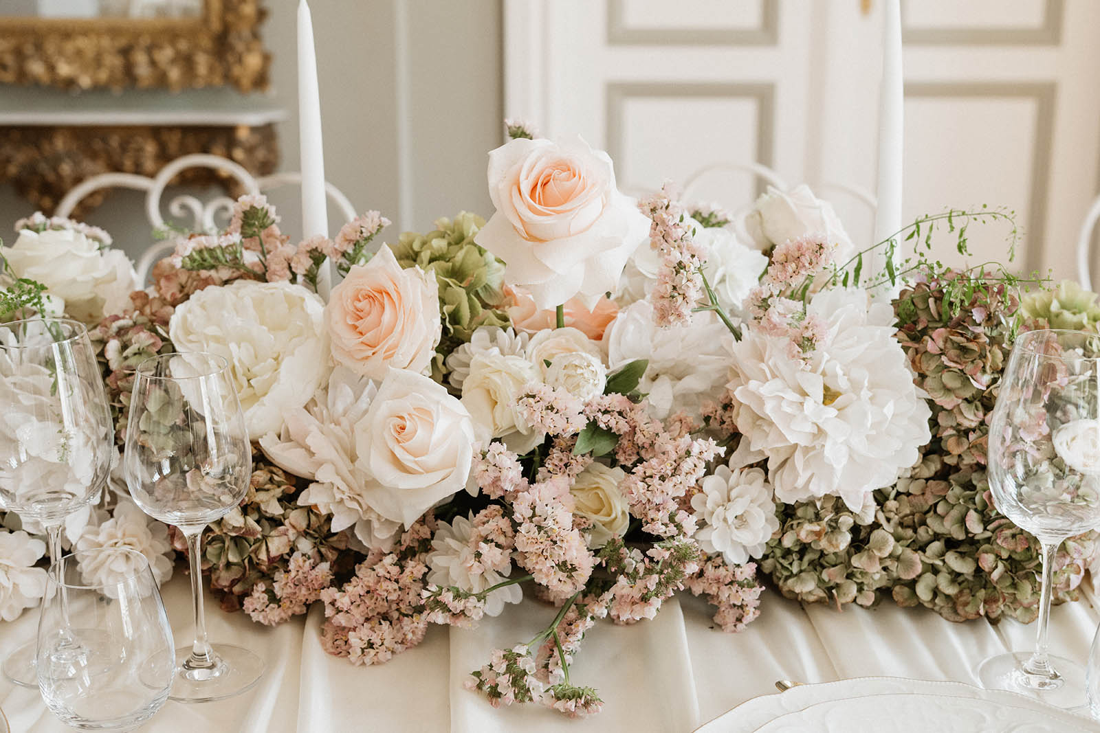 Blumengesteck aus frischen Rosen und getrockneten Hortensien in soften Rosé-, Creme- und Grüntönen für eine romantische Hochzeitstafel